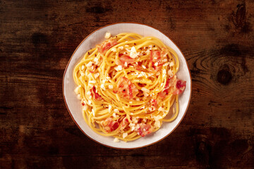 Wall Mural - Carbonara pasta dish, traditional Italian spaghetti with pancetta and cheese, overhead flat lay shot on a rustic background