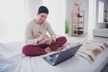 Canvas Print - Photo of attractive nice man after sleep working home sitting on soft comfy bed in white room indoors