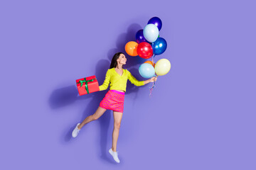 Sticker - Photo of lovely positive cheerful girl wear trendy clothes hold balloons look empty space isolated on purple color background