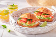 Tasty and hot french croissant with avocado, salmon and dill