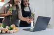 © itchaznong - mother and daughter arrange flowers together as a hobby. mother and daughter spend free time doing flower arranging activities together and looking at laptop