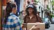 © kittikunfoto - A delivery person in a cap hands over a package to a recipient on a city street, capturing a moment of cheerful interaction between them.