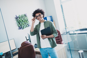 Wall Mural - Photo of handsome cool assistant dressed khaki shirt glasses holding clipboard reading documents indoors workstation workplace