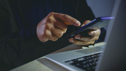 Hands using a smartphone and laptop simultaneously for secure login.