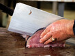 detail of hand of a fishmonger chopping swordgish at fresh fish seafood at Ortigia Syracuse sicily fish market Italy