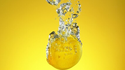 Poster - Super Slow Motion of Falling Whole Lemon Into Water, Isolated on Green Background. Filmed on High Speed Cinema Camera, 1000 fps.