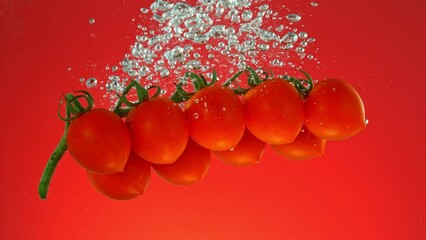 Poster - Super Slow Motion of Falling Cherry Tomatoes. Splashing Into Water on Colored Background. Filmed on High Speed Cinema Camera, 1000 fps.