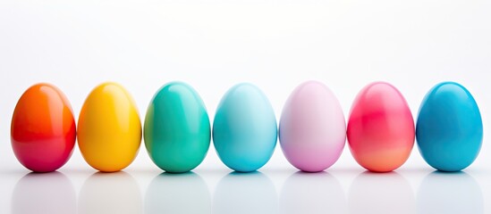 A variety of colorful Easter eggs including blue red green cyan and pink are neatly arranged on a white background allowing for ample copy space in the image