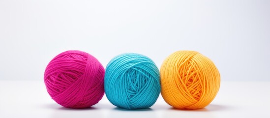 A plain white background with copy space hosts three vibrant balls of woolen yarn