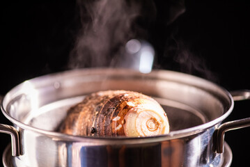 Wall Mural - Steamed taro tuber in boiling pot steams up as a chef opens the lid of a pot.