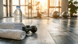 © Jullia - Sport, fitness, healthy lifestyle and bodybuilding concept - close up of bottle with water, towel, dumbbells on wooden floor in gym background. horizontal banner