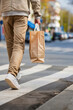 © Degimages - Man, legs and shopping bags in street of city, pedestrian in crosswalk for travel.