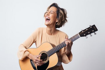 Wall Mural - Portrait of a joyful woman in her 40s playing the guitar in white background