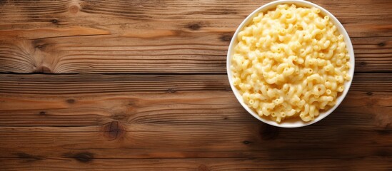 A top view image of a ceramic bowl filled with mac and cheese resting on a rustic wooden surface The background sets a nostalgic tone with its aged white wood texture leaving ample space for text pla