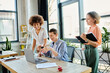 © Bliss - Diverse group of businesswomen gathered around a table, focused on a laptop screen.