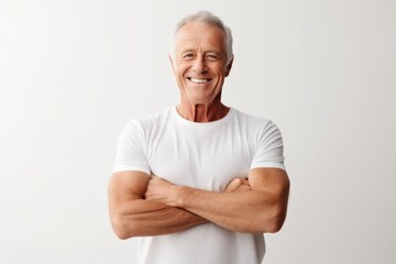 Wall Mural - Portrait of a grinning man in his 60s with arms crossed over white background