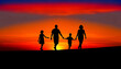 Silhouette of a family walking hand-in-hand against a sunset background. The family consists of two adults and two children