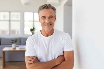 Wall Mural - Portrait of a blissful man in his 50s with arms crossed while standing against modern minimalist interior