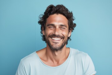 Wall Mural - Portrait of a blissful man in his 30s smiling at the camera in front of pastel blue background