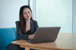 © PIPAT - Asian young beautiful happy professional successful businesswoman designer sitting smiling at workstation desk using laptop notebook computer and smartphone working remotely online at home office