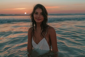 Poster - A woman standing in the ocean at sunset. Perfect for travel and relaxation concepts