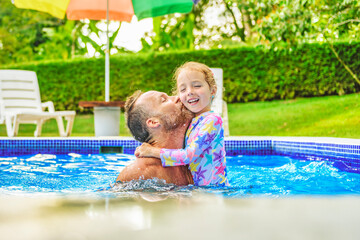 Wall Mural - father with little girl in pool on sunny day.