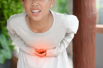 Man is holding his hand on his stomach and has a pained expression due to stomach pain It is caused by gastritis or inflammatory bowel disease in outdoor house background.