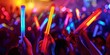 © Anastasiia - Hands Holding Glow Sticks at Rave with Blurred Dancing Crowd in Close-up Shot. Concept Rave Photography, Glow Sticks, Close-up Shot, Hands Holding, Blurred Crowd