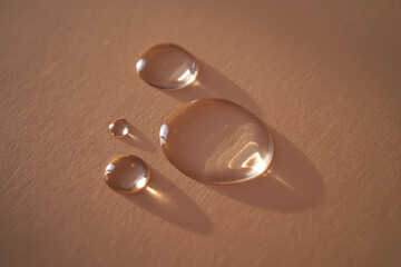 Beautiful volumetric drops of cosmetic product on a beige background.