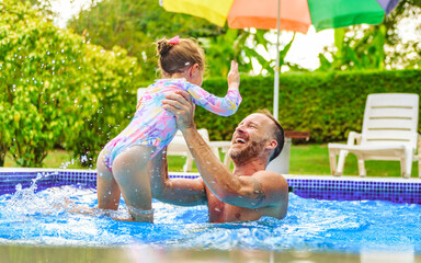 Wall Mural - father with little girl in pool on sunny day.