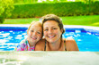 mother with little girl in pool on sunny day.
