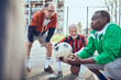 © Davor - Senior soccer team taking a break and strategizing during game on urban court