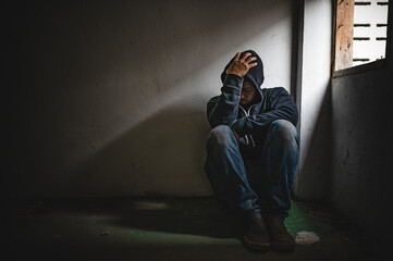 Asian man addict drug in the deserted place,A junkie feels alone in this world,Sad young man sitting in the corner of the room,People are stressed and have depression