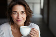 © vejaa - Smiling middle aged woman holding white blank coffee cup at home. Mockup