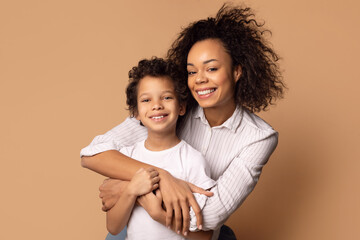 a joyful african american mother is tightly hugging her curly-haired young son, who radiates happine