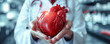 Hands of a doctor holding human heart. Health and cardiological diseases concept.