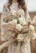 Luxurious wedding bouquet of white and creme various flowers in the hands of a bride in a wedding dress.