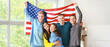 © Pixel-Shot - Happy friends with USA flag at home. Independence Day celebration
