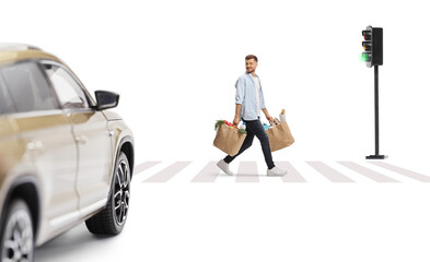 Wall Mural - Young man crossing a street with grocery bags and looking at a vehicle