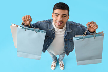 Sticker - Handsome young man with shopping bags on blue background