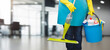 Cleaning woman with mop and cleaning supplies standing.