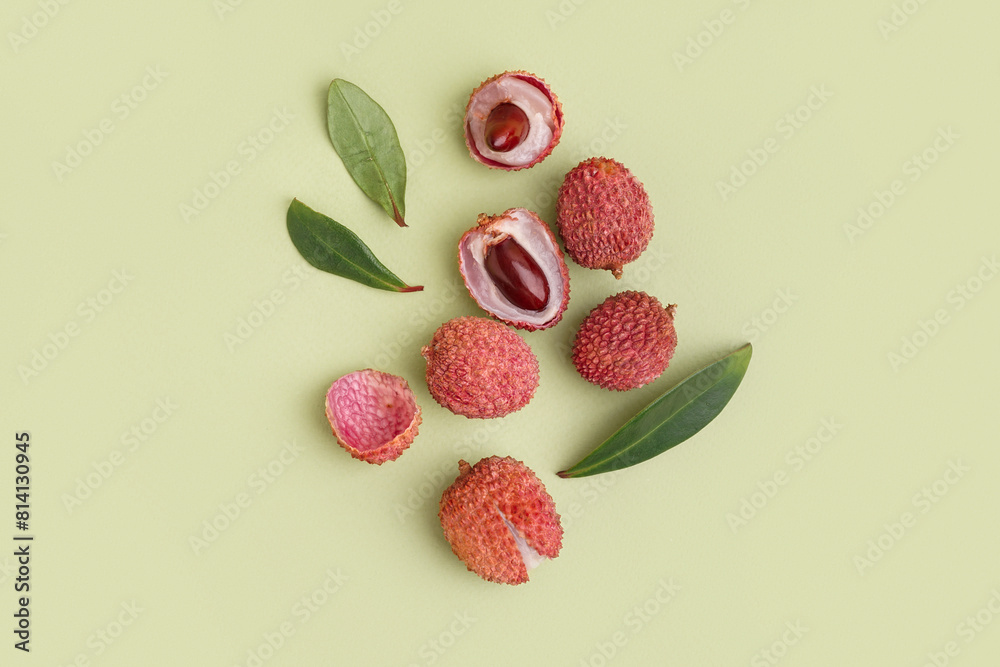Tasty litchi fruit and leaves on green background