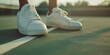 © Larisa - Close-up of white sneakers on tennis court line at sunset.