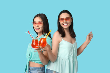 Sticker - Beautiful young women with glasses of cocktail on blue background. Summer party