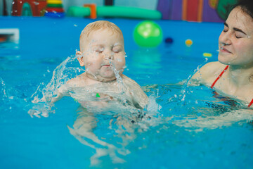 Wall Mural - Swimming pool for babies. A baby learns to swim with a coach