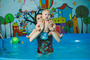 Wall Mural - Swimming pool for babies. A baby learns to swim with a coach