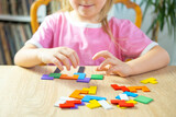 Fototapeta Na ścianę - little 5 year old girl playing at home with wooden blocks, child's hand explore intricate world colorful wooden puzzle, nurturing creativity, imagination and problem-solving skills