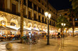 © JackF - Evening view of bustling Placa Reial in Barcelona with well-lit cafes and people enjoying leisurely stroll. Favorite place for locals and tourists alike