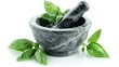 Sweet basil leaves in rock mortar with pestle on white background.