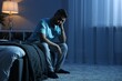 © New Africa - Frustrated man sitting on bed at night